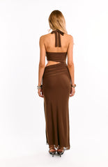 Back view of a girl in a brown cut out maxi dress. This elegant evening gown highlights the open back from the halter neck and a form-fitting skirt. An eye-catching option for a formal or cocktail party.