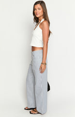 Model wears blue and white striped pants with a white top- brown belt- and matching handbag- showcasing stylish wide-leg trousers.