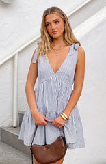 Model wearing a navy blue and white stripe flowy mini dress with adjustable tie shoulders paired with gold jewellery