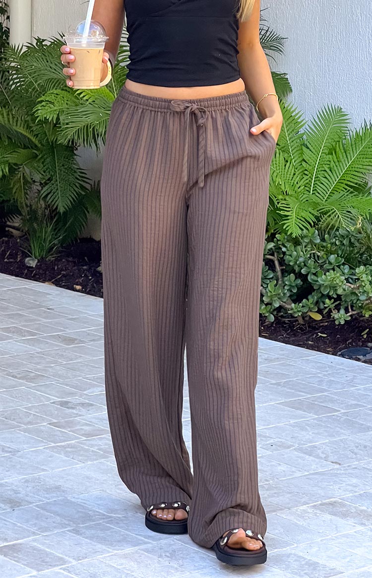 A front view of flowing- wide-leg brown ribbed pants featuring a drawstring waist and visible vertical ribbing.