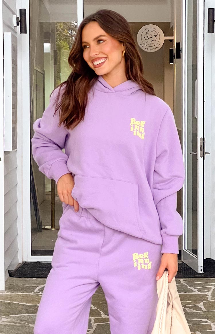 Model in purple tracksuit set, smiling and looking to the side.