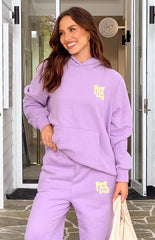 Model in purple tracksuit set, smiling and looking to the side.