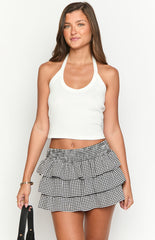 Model wearing a black off-shoulder knitted sweater with a black and white gingham ruffled mini skirt