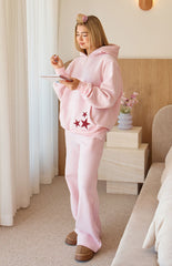 A pair of light pink wide-leg flared sweatpants perfectly worn as part of a matching set. Our pants are made of a soft fleece or jersey material.