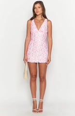 Brunette model wearing a pink floral lace mini dress and gold jewellery.