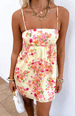 Girl wearing a yellow floral satin mini dress paired with gold jewellery and a white handbag