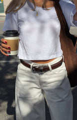 Girl in a simple white crop top and stylish white jeans with a belt a casual chic outfit for a Summer brunch