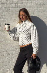 Woman in a trendy white polka dot high-neck jacket and black trousers a professional yet stylish look for work or events