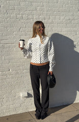 Girl wearing a chic white polka dot long-sleeve shirt and black tailored pants an elegant outfit for a Fall gathering