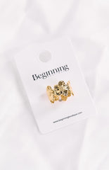 A gold flower-shaped ring displayed on a white 'Beginning Boutique' branded card.