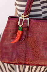 A red chilli shaped bag charm with a gold chain and clasp. This quirky accessory is a fun way to decorate a handbag. A perfect gift to spice up a festival outfit or everyday look.