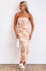 Blonde model wearing a strapless yellow mesh maxi dress with a floral design paired with white heels and gold jewellery