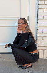 Woman wearing a black ribbed off-shoulder long sleeve top with dark trousers a versatile staple for a Fall wardrobe