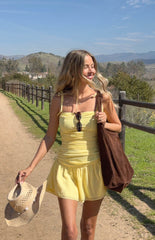 model wearing a yellow chiffon mini dress with ruched and ruffle skirt details