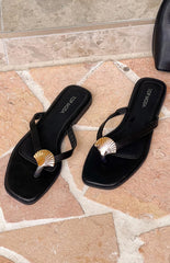 Two black flip-flops with gold and silver seashell embellishments are positioned on a light brown tiled surface. The brand "TOP MODA" is visible on the inner sole of each shoe.