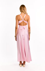A girl shows the back of a light pink formal maxi dress. This stunning evening gown has a beautiful cross over back detail with an adjustable tie. An elegant choice for prom or a graduation ball.