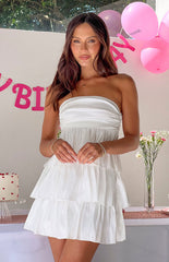 Brunette girl wearing a white strapless mini dress at a birthday party.