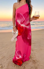 A fuchsia one-shoulder maxi dress with bold red orchid prints- featuring a loose- flowing silhouette- ideal for a tropical evening event.