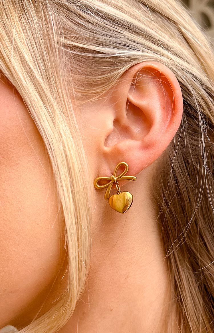 gold plated push back earrings with a bow detail and dangly heart