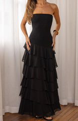 Our female model wearing a black strapless maxi dress with a shirred or smocked bodice and a tiered ruffled skirt.