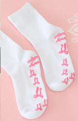 white yoga socks with pink bow shaped grips on the bottom and a graphic 'beginning boutique' grip