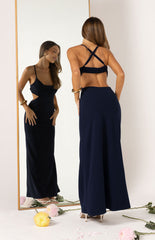 Girl in a long navy evening gown made from crepe fabric with a high neckline and a backless design.