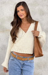 Model wearing a cream chunky knit wrap sweater with a V-neck