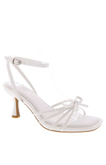 A pair of white strappy stiletto heels with a delicate front bow detail and a square toe.