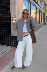 Smiling girl wearing a grey boucle bomber jacket over a crop top and white jeans a cozy look for a cool Autumn day