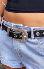 girl wearing light blue denim shorts paired with a black and silver sparkle belt and a black top