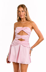 Model wears a light pink strapless mini dress. This fun party dress features a small cut out below the bust and a fit and flare silhouette. A perfect choice for a birthday celebration or a night out.