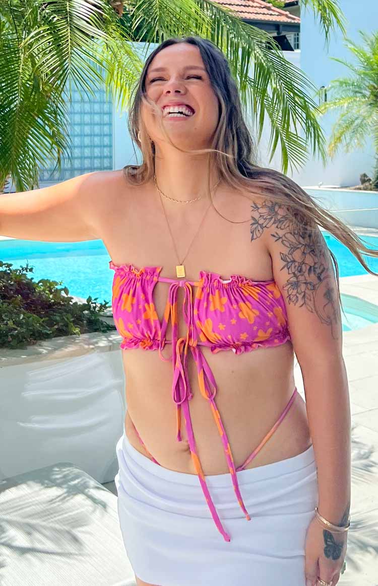 model in pink floral strapless bikini top and bottoms posing by pool