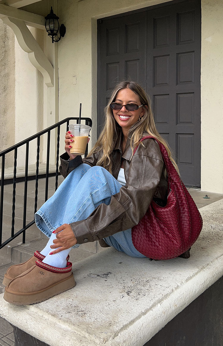 Faux leather oversized brown bomber jacket. Worn by model walking the street.