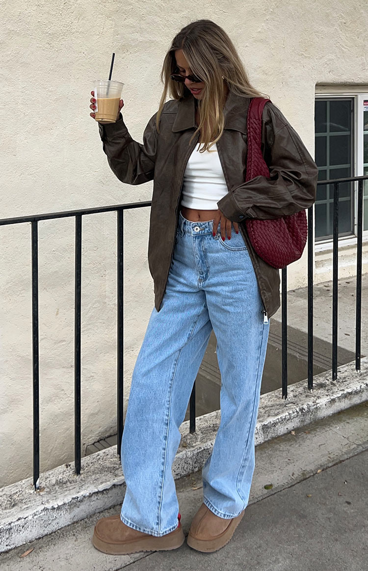 Faux leather oversized brown bomber jacket. Worn by model walking the street.