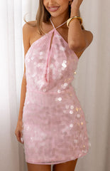 Our female model wearing a pale pink mini dress with a halter neckline and an all-over sequin embellishment. The dress features a keyhole detail and a gathered or ruched bust.