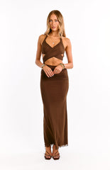 Model wears a chocolate brown maxi dress with a halter neckline. This formal dress features a daring waist cut out and a fitted silhouette. A perfect choice for a wedding guest or special event outfit.