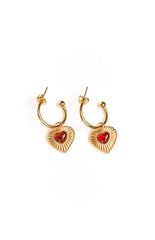 A pair of gold hoop earrings with small red heart pendants. This cute jewellery is a great addition to a party outfit or valentines day look. The charm is a vibrant red colour.