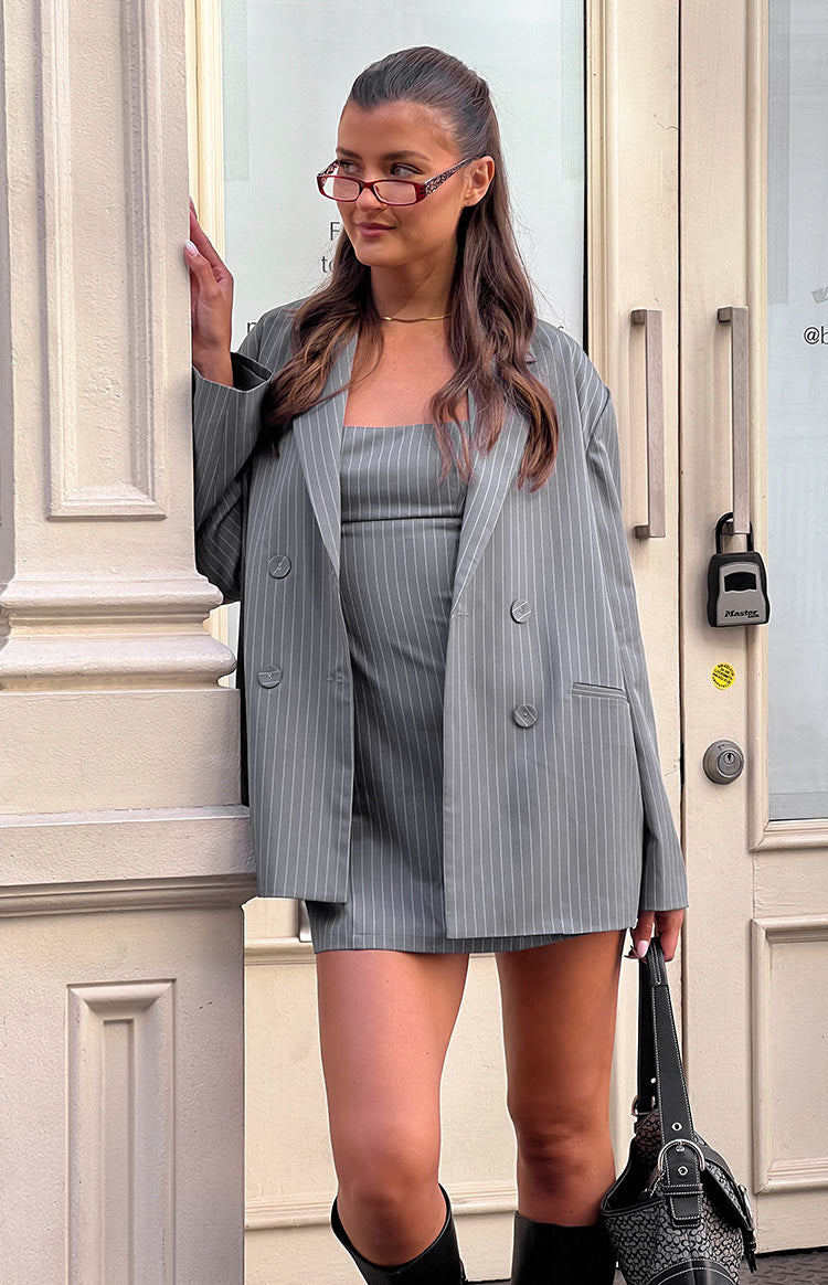 Girl facing away in grey striped mini dress and black boots
