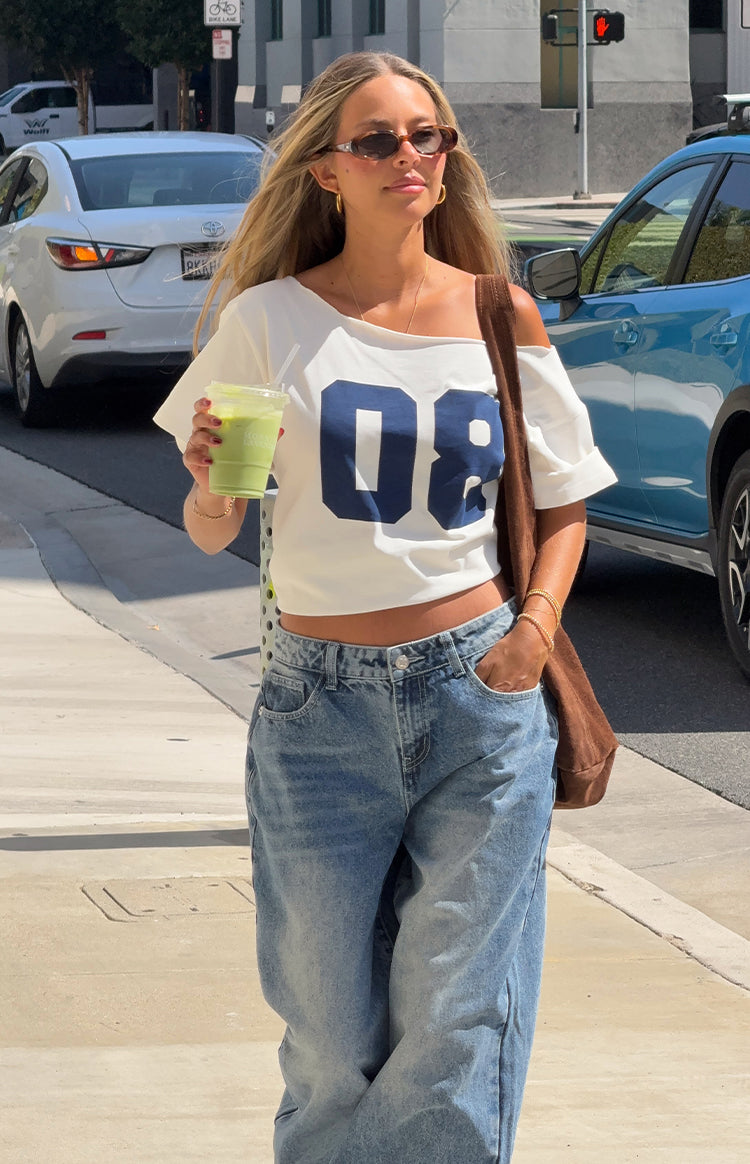 Stylish woman in a white off-shoulder 08 crop top and baggy jeans for a casual Spring brunch outfit