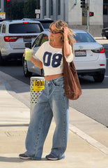 Fashionable girl wearing a white 08 graphic crop top and loose denim jeans ideal for a relaxed Autumn day