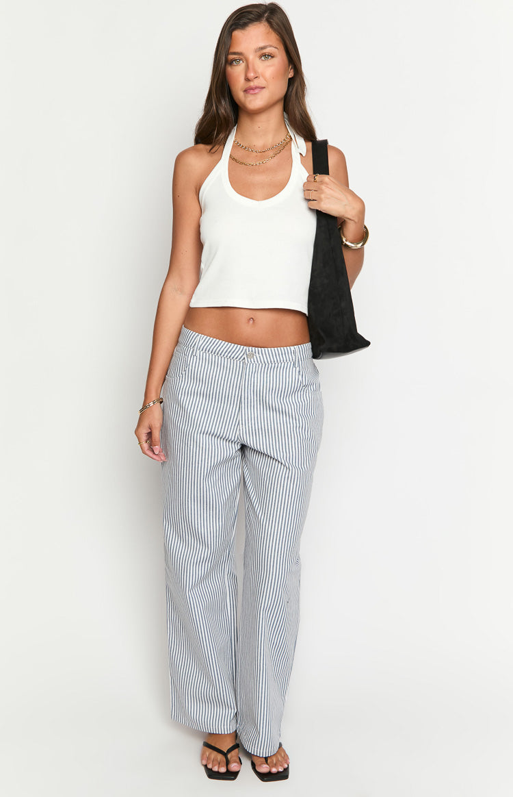 Model wears blue and white striped pants with a white top- brown belt- and matching handbag- showcasing stylish wide-leg trousers.