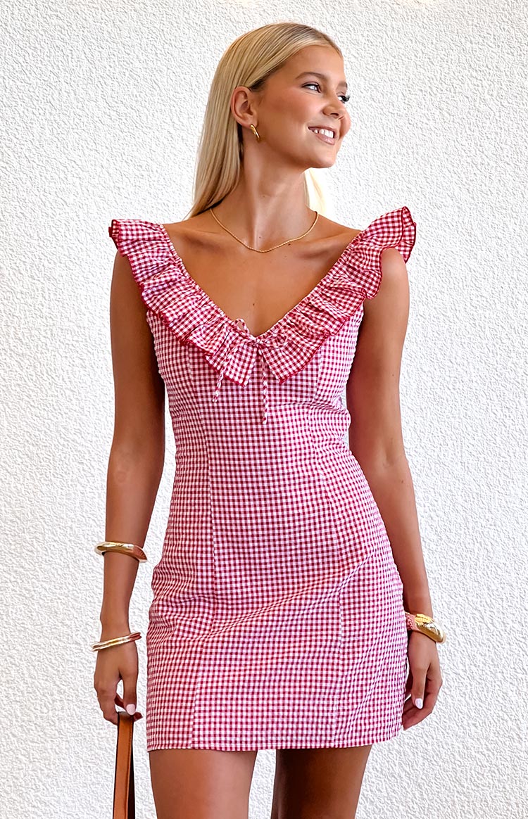 Blonde model wearing a red gingham mini dress with a frill detail along the neckline