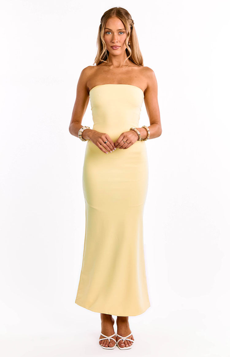 A model wears a bright yellow crepe maxi dress. This formal dress features a strapless straight neckline and a luxurious crepe fasbric. An elegant choice for a wedding guest or graduation dress.
