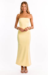 A model wears a bright yellow crepe maxi dress. This formal dress features a strapless straight neckline and a luxurious crepe fasbric. An elegant choice for a wedding guest or graduation dress.