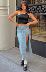 Brunette Model is posed in a blue denim midi skirt. The midi skirt features a cutout/leg split on the left side.