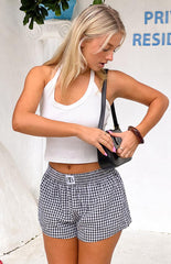 A comfortable yet stylish outfit featuring a white ribbed scoop-neck tank top and black and white gingham print shorts with an elasticated waist.