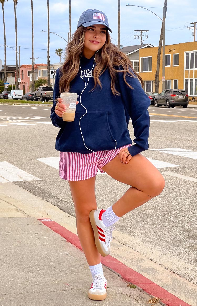 Model wearing a navy hoodie with a white USA graphic on the front paired with red and white striped shorts