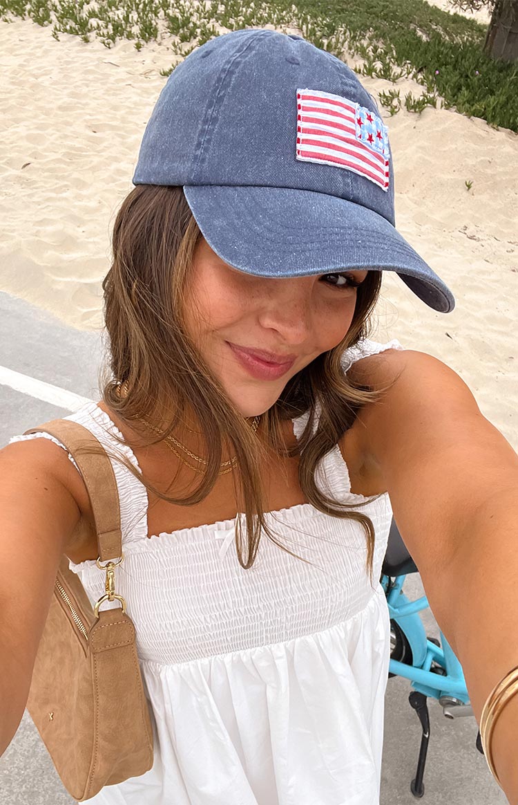 Girl wearing a washed navy coloured baseball cap with an embroidered USA flag design