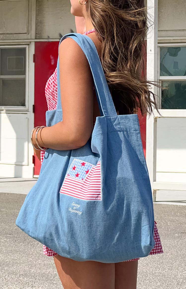 Model wearing a denim tote bag with a red and blue USA flag applique