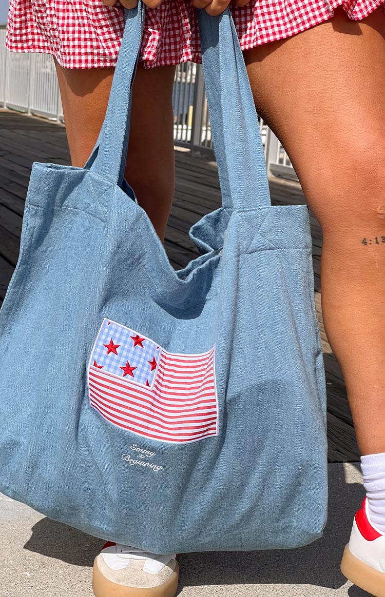 Model wearing a denim tote bag with a red and blue USA flag applique